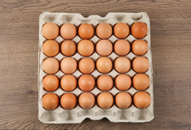 Photo of Raw chicken eggs on wooden table, top view