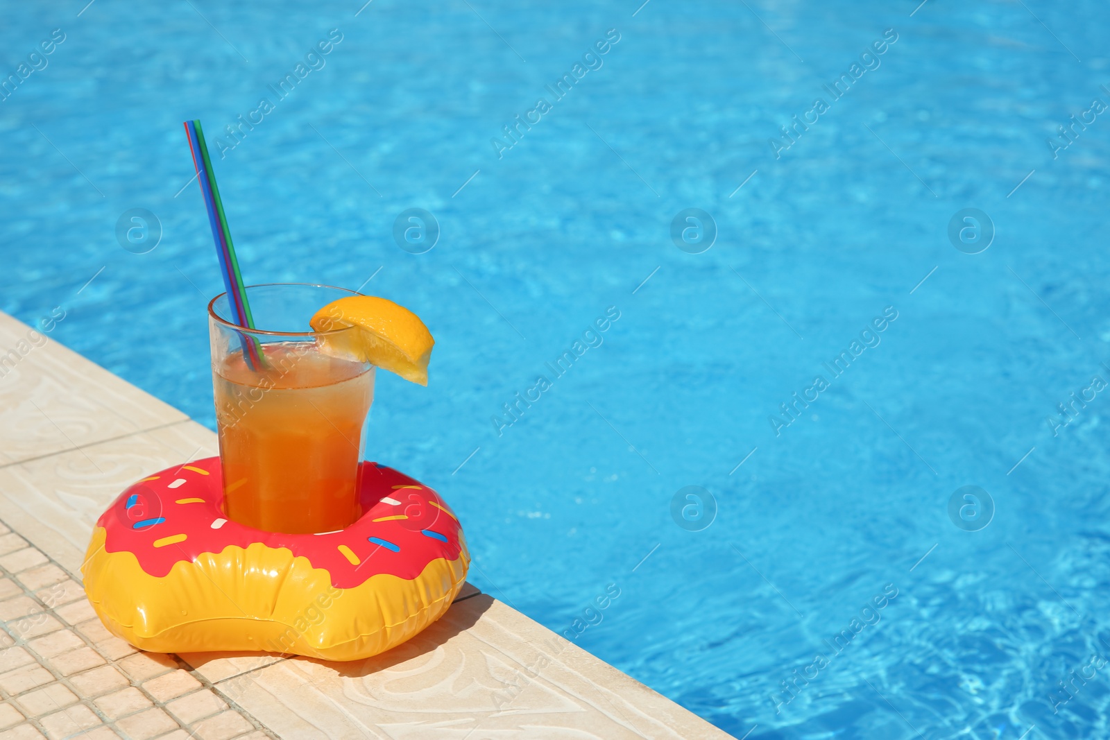 Photo of Tasty refreshing cocktail on edge of swimming pool