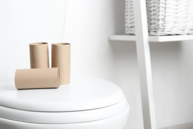Photo of Empty paper rolls on toilet seat in bathroom