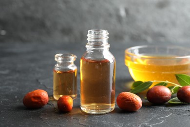 Photo of Jojoba oil and seeds on dark grey table