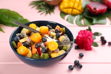 Delicious exotic fruit salad on pink wooden table