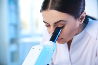 Photo of Female scientist using microscope in chemistry laboratory, space for text