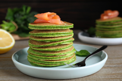 Photo of Tasty spinach pancakes with salmon on wooden table