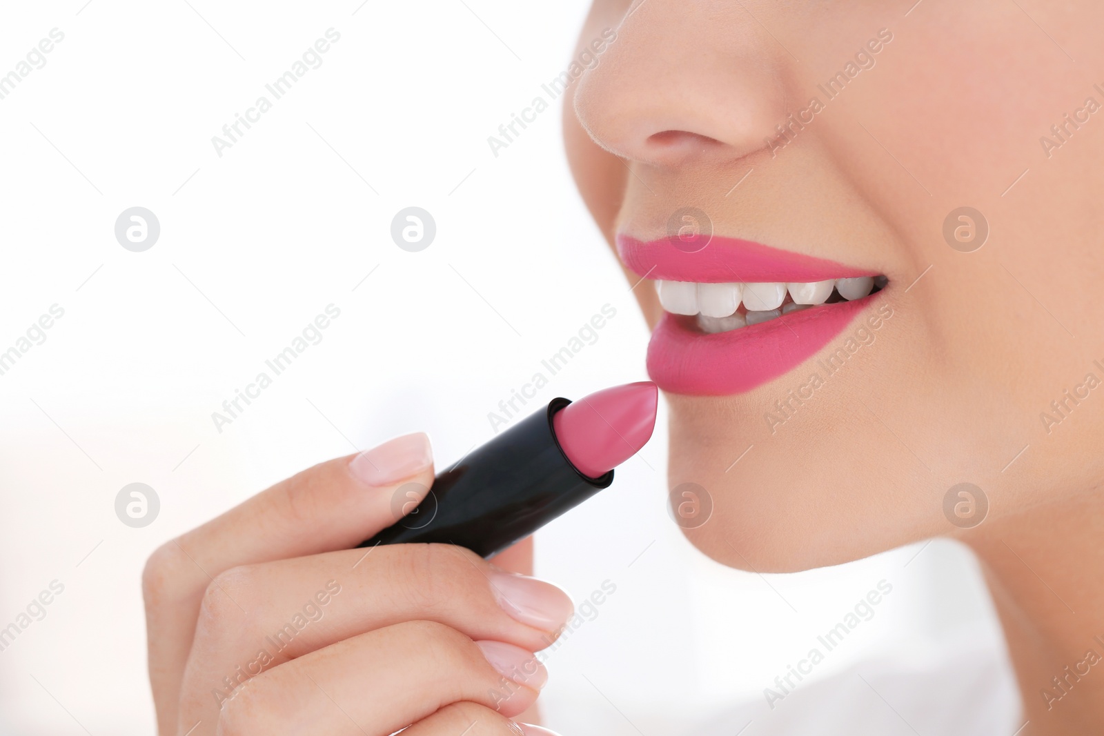 Photo of Beautiful woman applying lipstick on light background, closeup