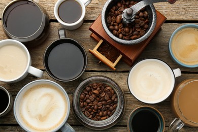 Photo of Different coffee drinks in cups, beans and manual grinder on wooden table, flat lay