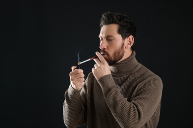 Photo of Man using cigarette holder for smoking on black background, space for text