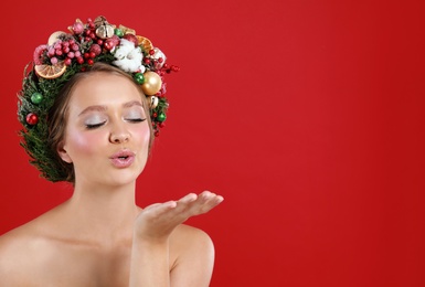 Photo of Pretty young woman wearing Christmas wreath on red background. Space for text