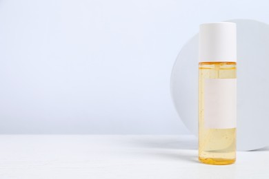 Photo of Bottle of cosmetic product on white wooden table. Space for text