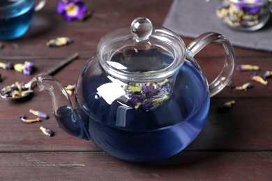 Photo of Organic blue Anchan in teapot on wooden table. Herbal tea