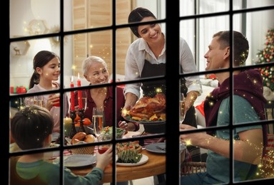 Image of Happy family enjoying festive dinner at home, view through window. Christmas celebration