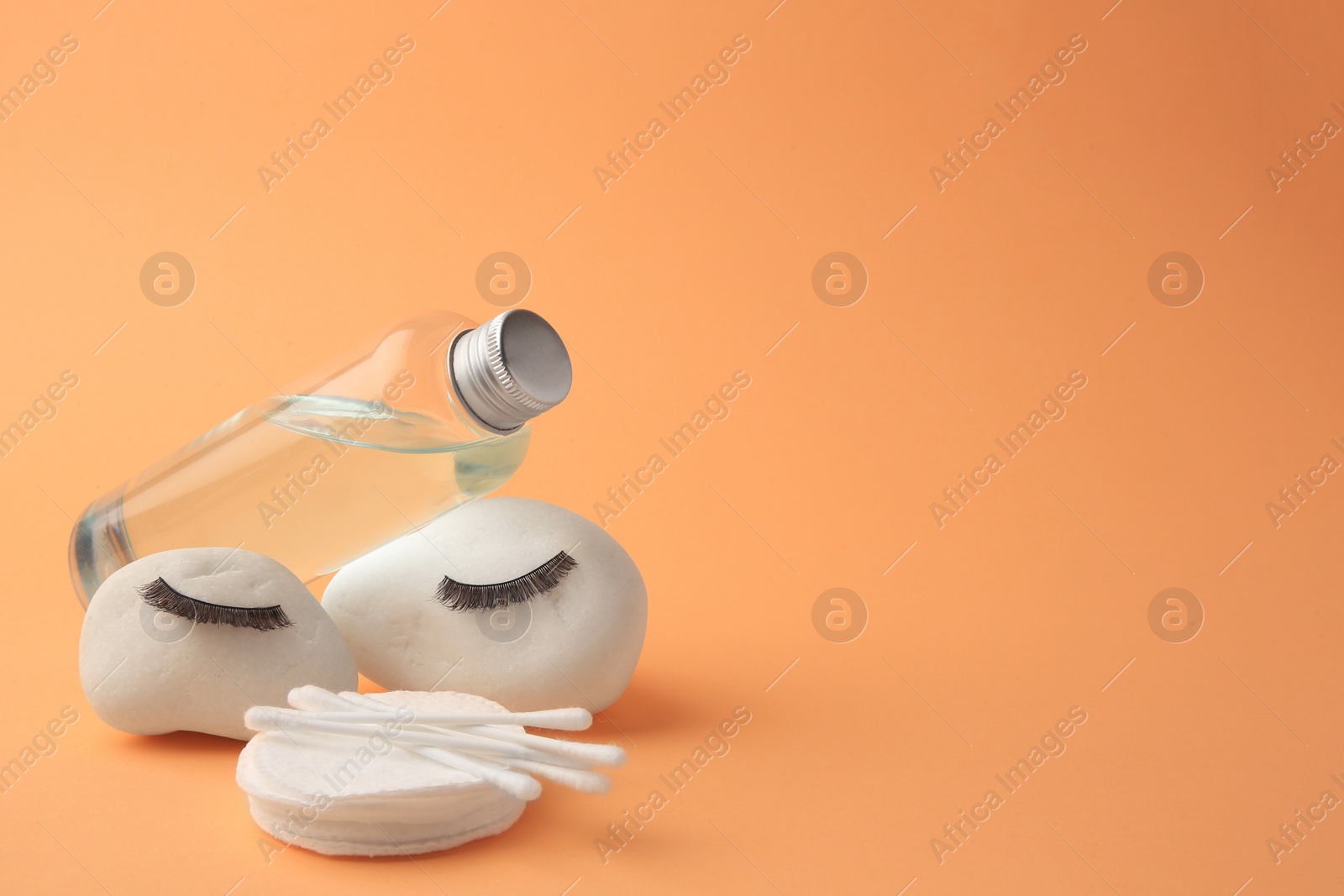 Photo of Composition with makeup remover and false eyelashes on pale orange background, space for text