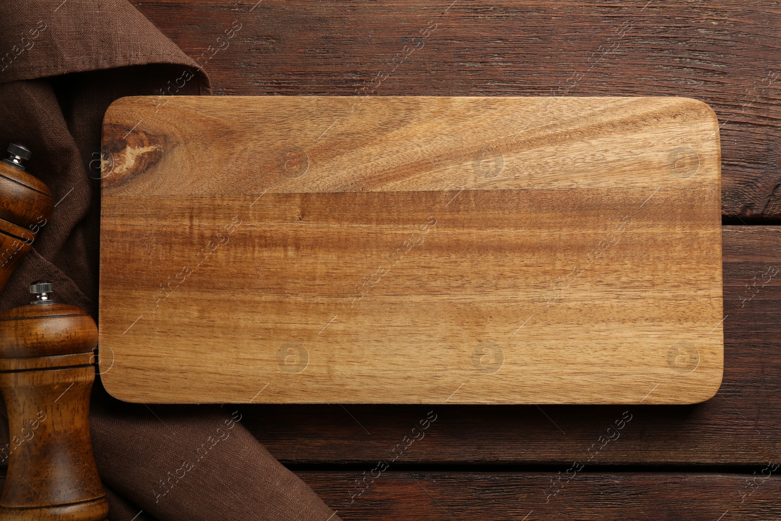 Photo of New cutting board and shakers on wooden table, flat lay