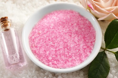 Photo of Bowl of aromatic sea salt, flower and bottle with spa product, closeup