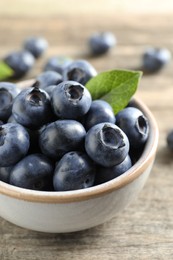 Photo of Bowl of tasty fresh blueberries on wooden table, closeup
