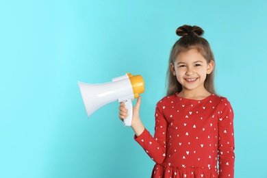 Photo of Cute funny girl with megaphone on color background. Space for text