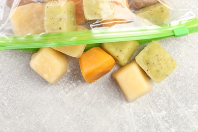 Photo of Different frozen fruit puree cubes in plastic bag on table, flat lay. Space for text