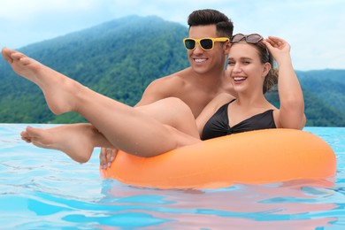 Image of Happy couple in outdoor swimming pool at luxury resort with beautiful view of mountains