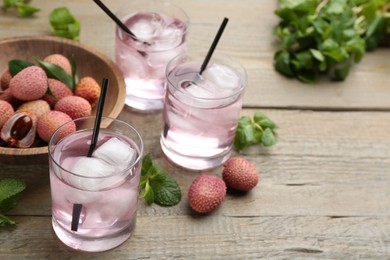 Photo of Delicious lychee cocktails and fresh fruits on wooden table. Space for text