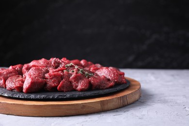 Photo of Pieces of raw beef meat and thyme sprigs on grey textured table against black background. Space for text