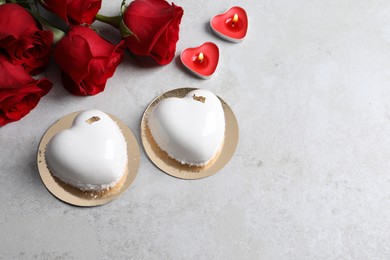 Photo of St. Valentine's Day. Delicious heart shaped cakes, candles and roses on light table, flat lay. Space for text