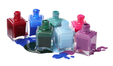 Photo of Puddle of different bright nail polishes and bottles isolated on white