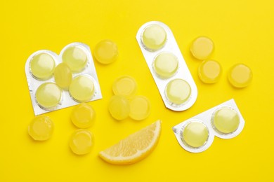 Photo of Many lemon cough drops on yellow background, flat lay