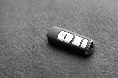 Photo of Modern car smart key on grey fabric. Space for text