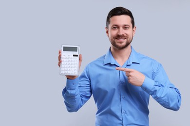 Photo of Happy accountant showing calculator on light grey background. Space for text