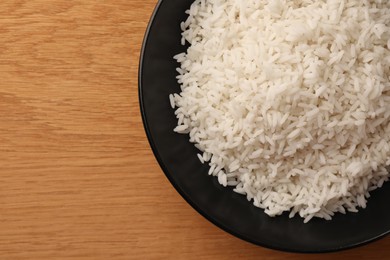 Plate with delicious rice on wooden table, top view. Space for text