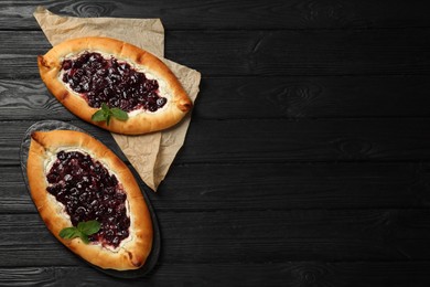 Photo of Delicious sweet cottage cheese pastry with cherry jam on black wooden table, flat lay. Space for text