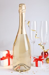 Photo of Happy New Year! Bottle of sparkling wine, glasses and festive decor on white background