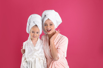 Photo of Emotional mother and daughter with facial masks on pink background