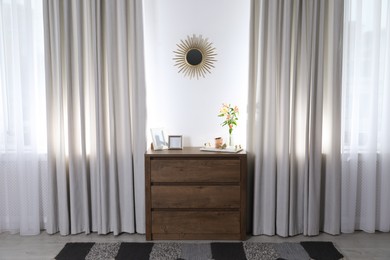 Photo of Stylish room interior with wooden chest of drawers and beautiful decor elements