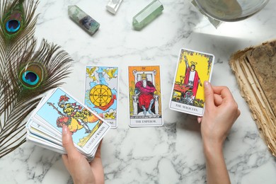 Photo of Woman with tarot cards at white marble table, top view