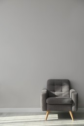 Photo of Stylish armchair near grey wall, space for text.  Interior element