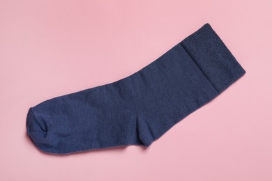 Photo of New dark blue sock on pink background, top view