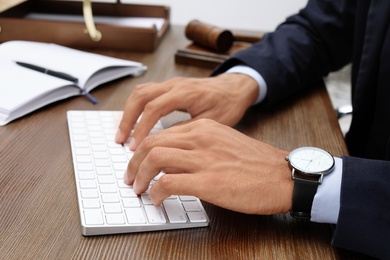 Photo of Male lawyer working with computer at table, closeup