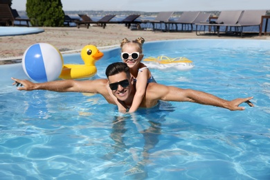 Photo of Happy man and his daughter in outdoor swimming pool on sunny summer day