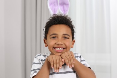 Photo of Cute African American boy with Easter bunny ears headband indoors