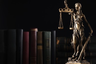Photo of Statue of Lady Justice near books on dark background, space for text. Symbol of fair treatment under law
