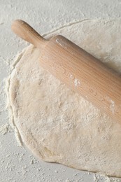 Photo of Raw dough and rolling pin on table