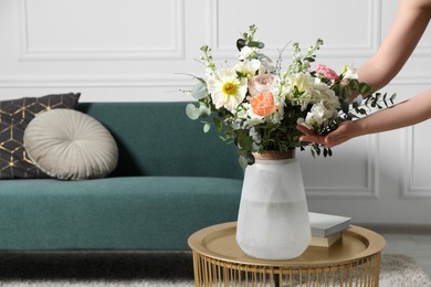 Photo of Woman arranging bouquet of beautiful flowers in vase indoors, closeup. Space for text