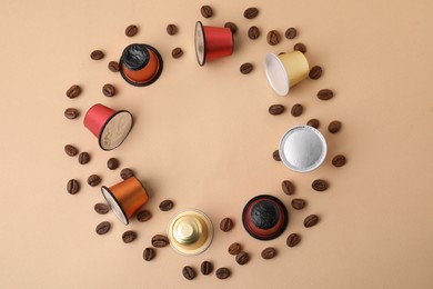 Photo of Frame made of many coffee capsules and beans on beige background, top view. Space for text
