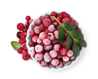 Photo of Frozen red cranberries in bowl and green leaves isolated on white, top view
