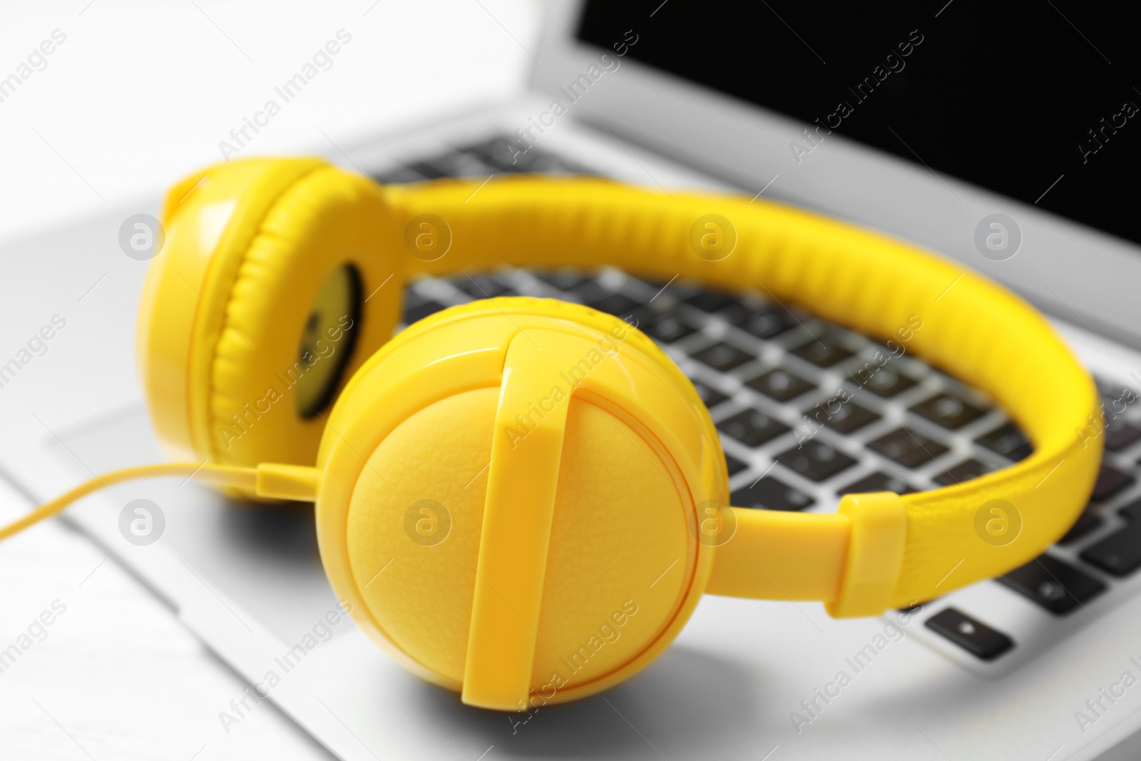 Stylish headphones on laptop, closeup. Modern technology Photo of Stylish headphones on laptop, closeup. Modern technology