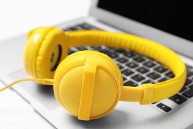 Photo of Stylish headphones on laptop, closeup. Modern technology