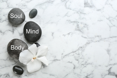 Photo of Stones with words MIND, BODY, SOUL on marble background, top view with space for text. Zen lifestyle