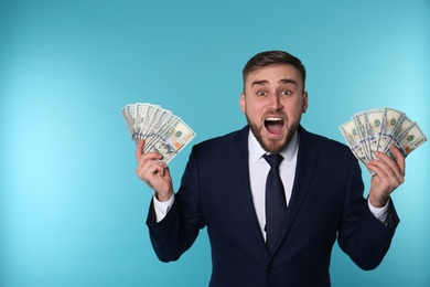Photo of Portrait of emotional young businessman with money on color background