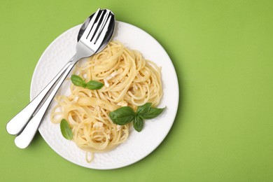 Photo of Delicious pasta with brie cheese and basil leaves on light green background, top view. Space for text
