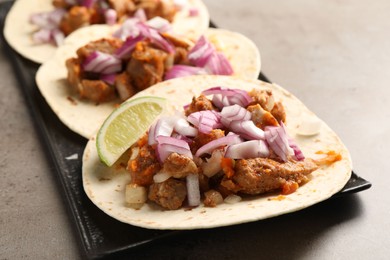 Photo of Delicious tacos with vegetables, meat and lime on grey textured table, closeup